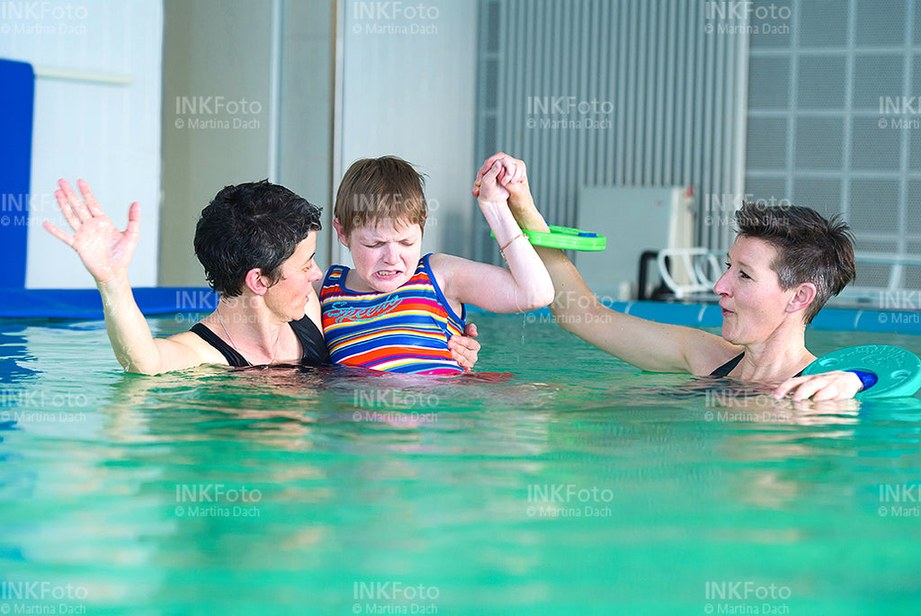 Frau mit Sehbehinderung zusammen mit 2 weiteren Frauen im Schwimmbad.