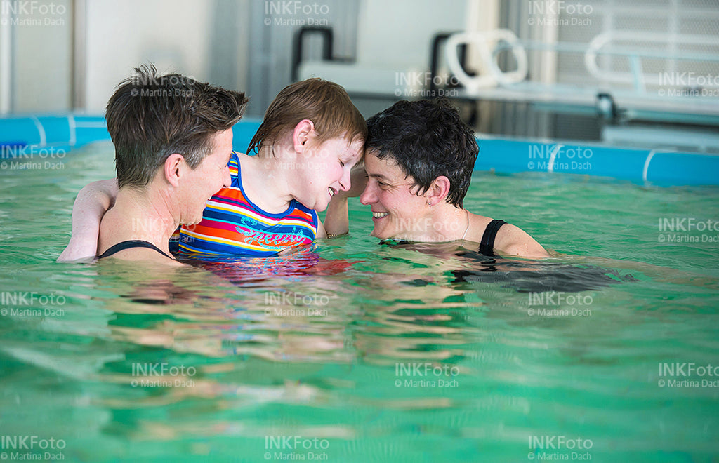 Frau mit Sehbehinderung zusammen mit 2 weiteren Frauen im Schwimmbad.