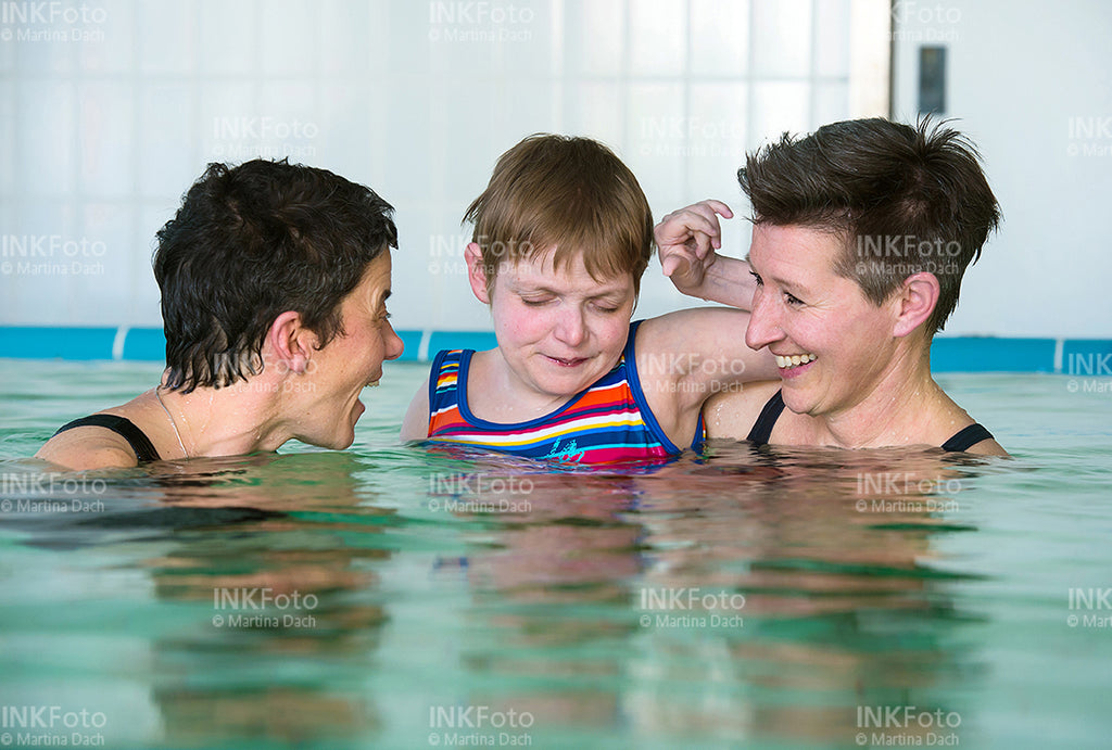 Frau mit Sehbehinderung zusammen mit 2 weiteren Frauen im Schwimmbad.