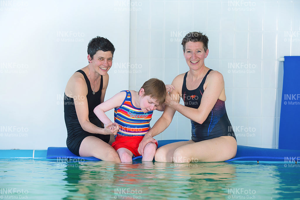 Frau mit Sehbehinderung zusammen mit 2 weiteren Frauen im Schwimmbad.