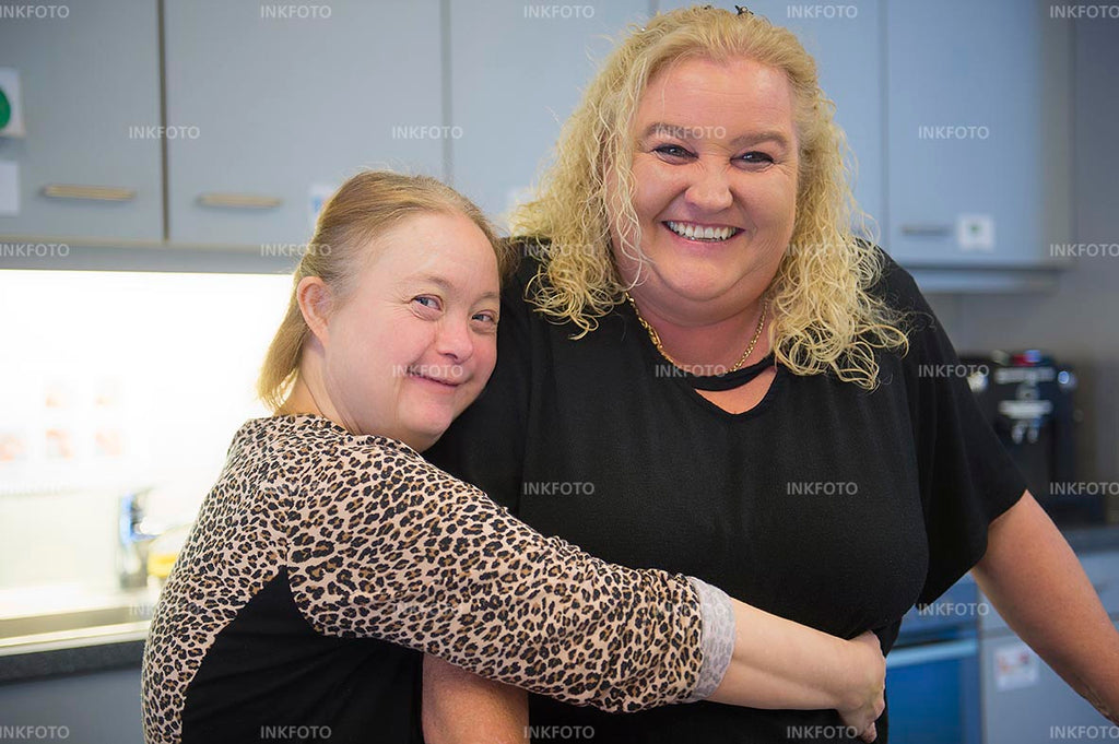 2 Frauen lächeln und umarmen sich.