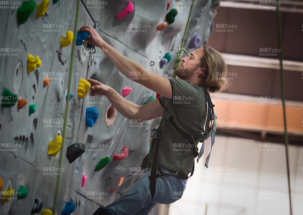 Junger Mann mit Klettergurt an der Kletterwand