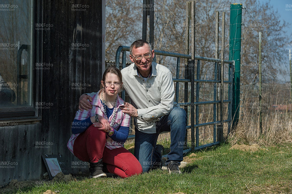 Vater und Tocher knien im Gras