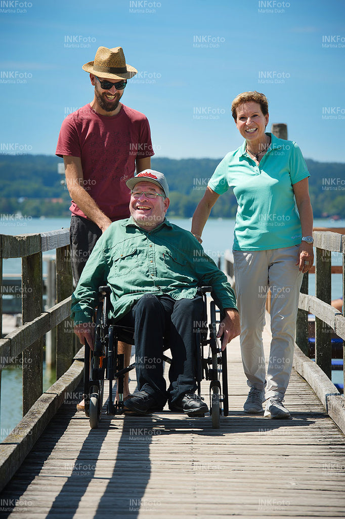 Mann im Rollstuhl am See unterhält sich mit einer Frau und einem Mann