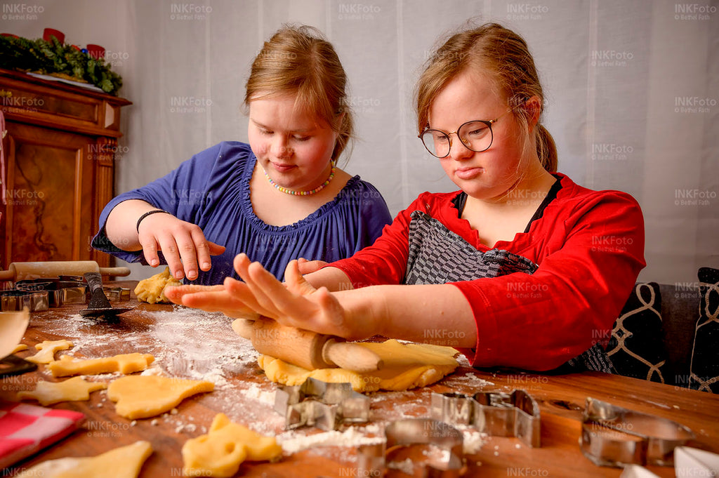 Zwei junge Mädchen beim Teigausrollen