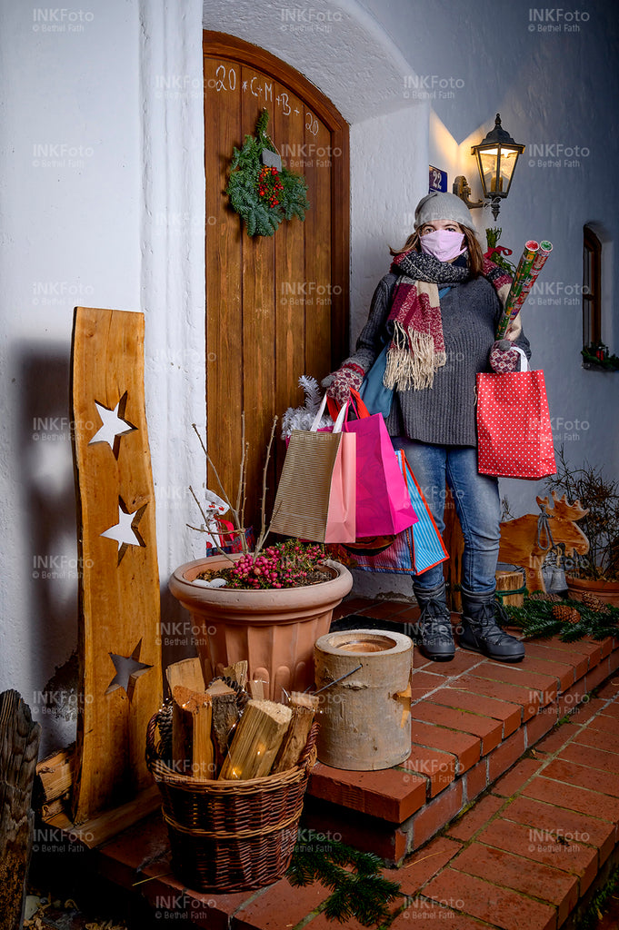 Junge Frau mit Mund-Nasen-Schutz mit Weihnachtseinkäufen