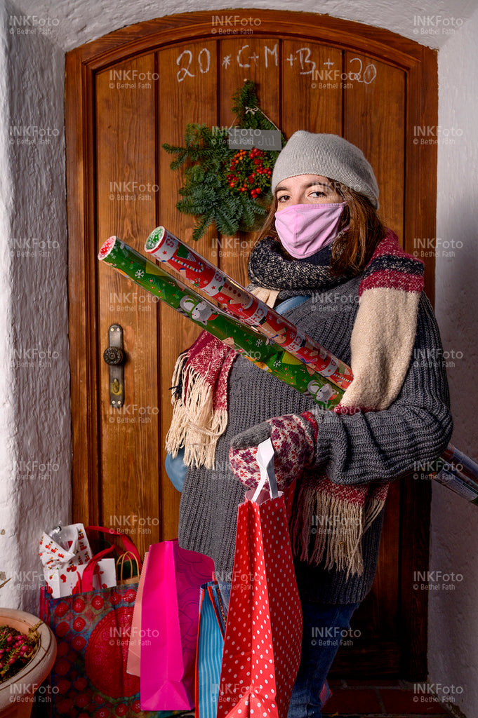 Junge Frau mit Mund-Nasen-Schutz mit Weihnachtseinkäufen