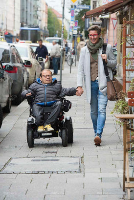 Mann im Rollstuhl mit Frau Hand in Hand in der Stadt. 