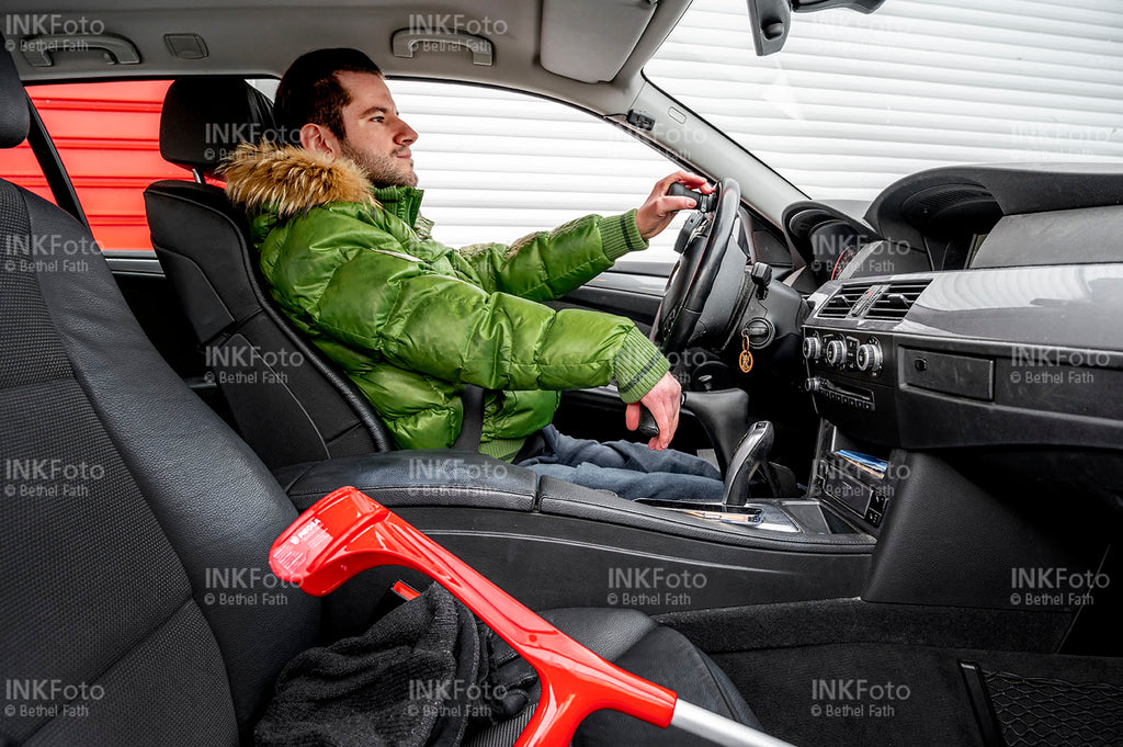 Junger Mann mit Krücken beim Autofahren.