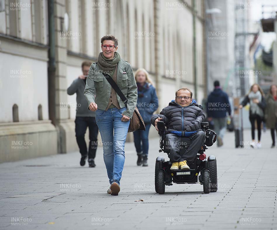 Mann im Rollstuhl mit Frau in der Stadt