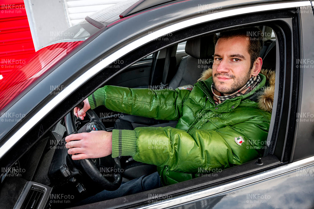 Blick ins Auto auf einen jungen Mann während er ein Auto fährt.