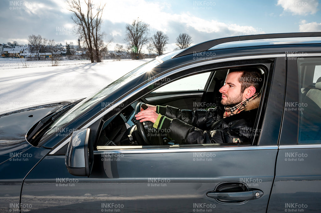 Blick ins Auto auf einen jungen Mann während er ein Auto fährt.