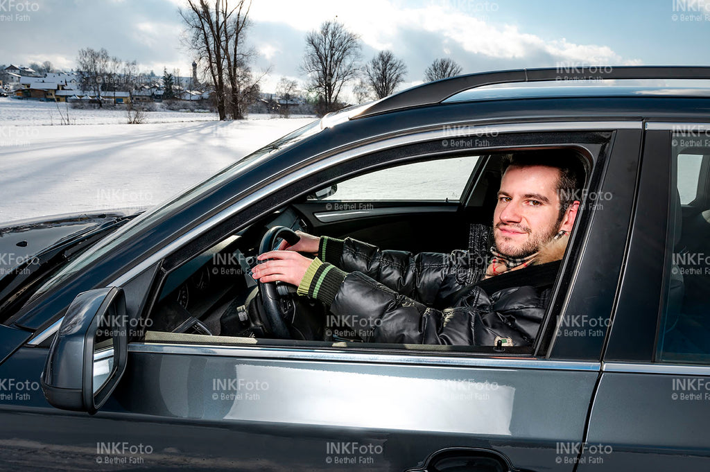 Blick ins Auto auf einen jungen Mann während er ein Auto fährt.