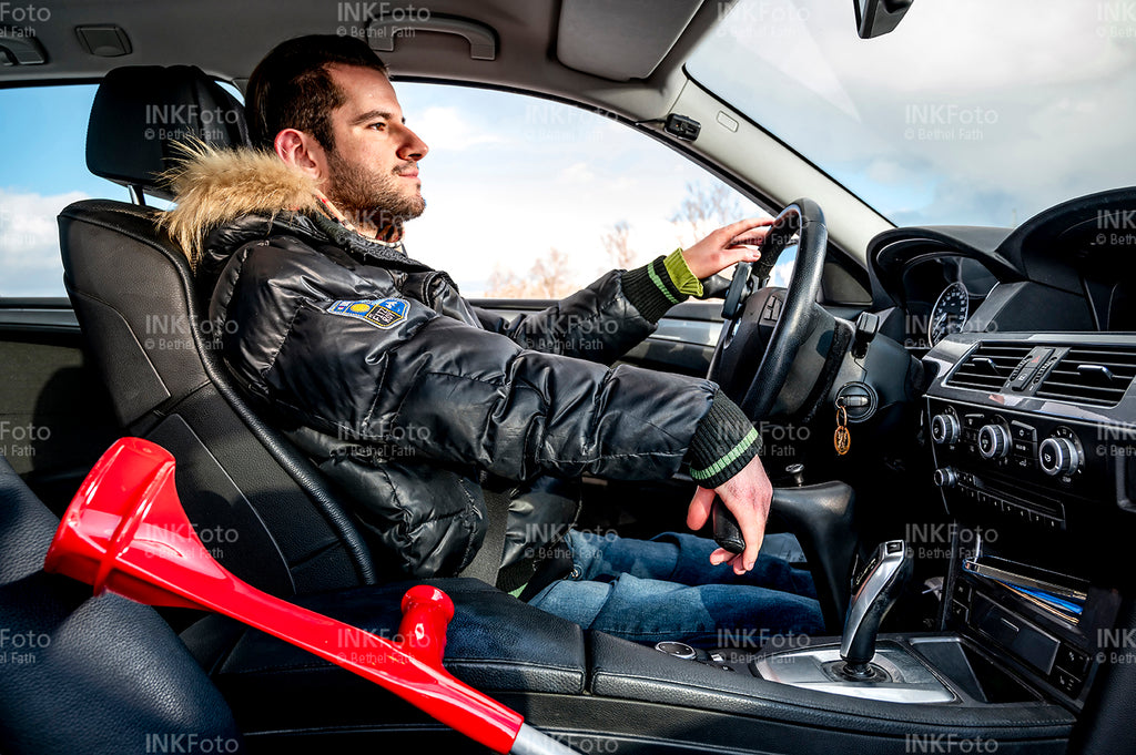 Junger Mann im Auto neben sich die Krücken auf dem Beifahrersitzt