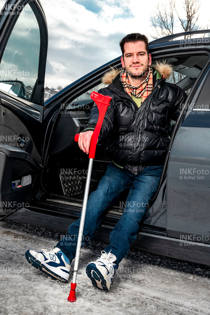 Junger Mann mit Krücke beim Aussteigen aus einem Auto.