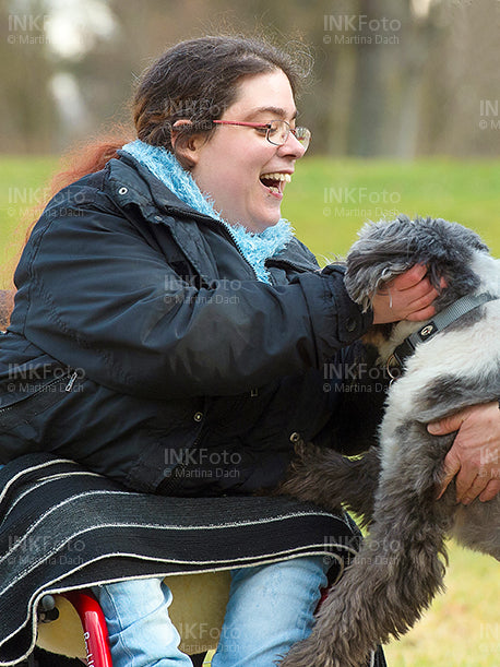 Junge Frau im Rollstuhl mit Hund im Park.