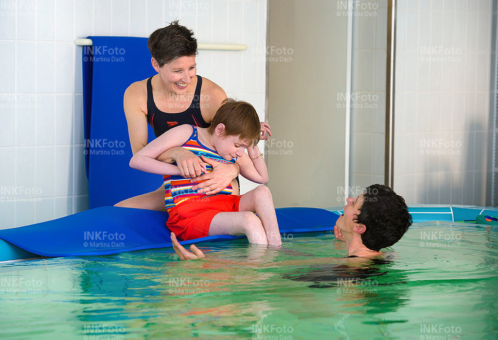 Frau mit Sehbehinderung zusammen mit 2 weiteren Frauen im Schwimmbad.