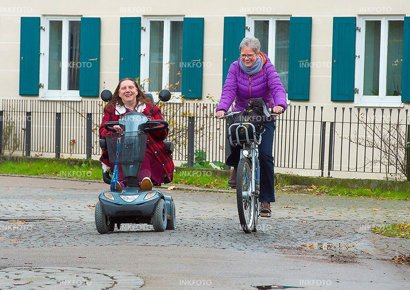 2 Frauen unterwegs in der Stadt mit Scooter und Fahrrad