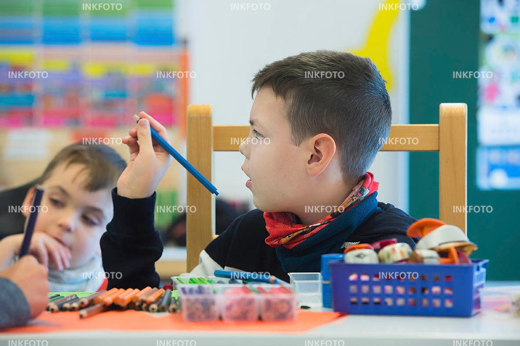 Kind malt im Kunstunterricht ein Bild mit Buntstiften.