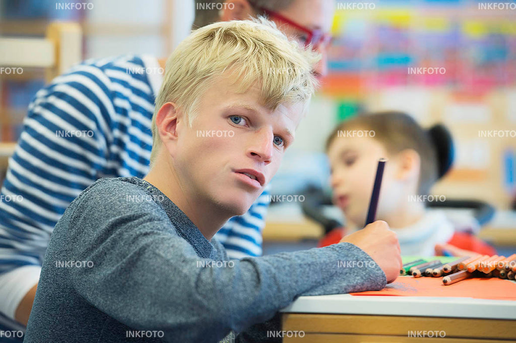 Jugendlicher malt im Kunstunterricht ein Bild mit Buntstiften.