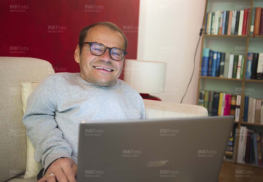 Lächelnder Mann mit Laptop im Homeoffice bei der Arbeit