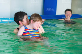 Frau mit Sehbehinderung zusammen mit 2 weiteren Frauen im Schwimmbad.