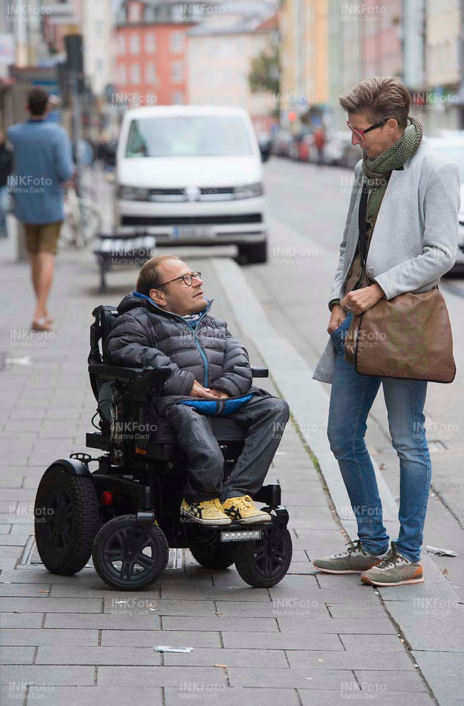Mann im Rollstuhl mit Frau in der Stadt