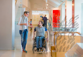 Mann im Rollstuhl mit Frau gehen durch ein Museum