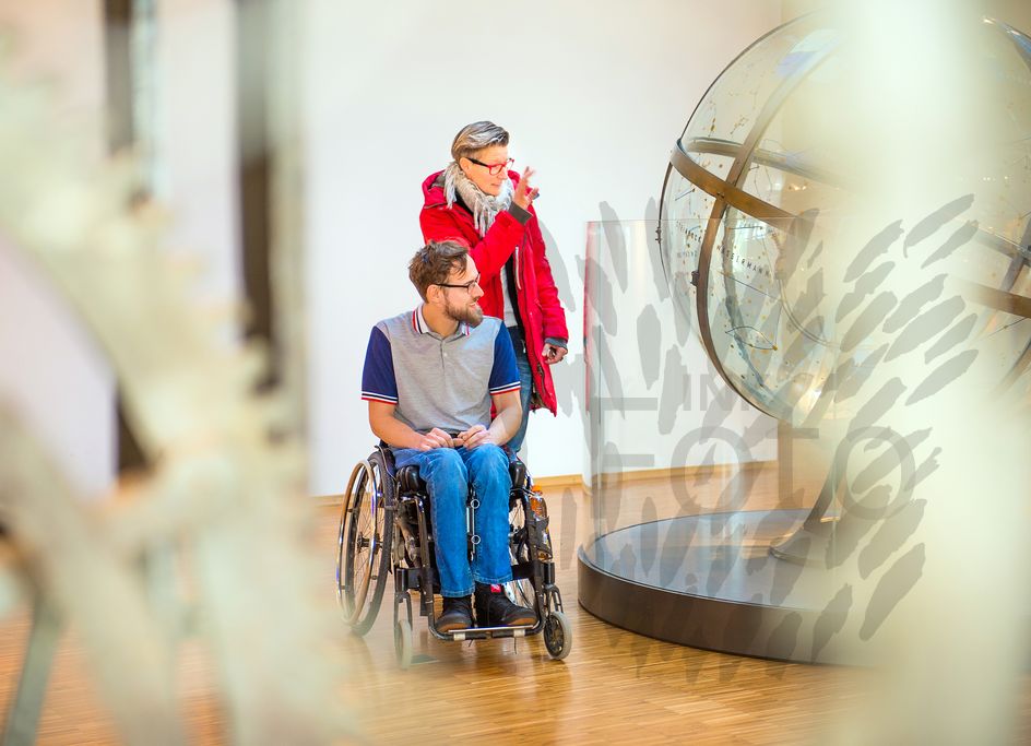 Mann im Rollstuhl und Frau in einem Museum