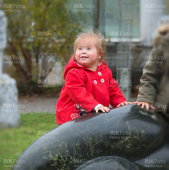 Kleines Mädchen mit roter Jacke im Park beim Spielen