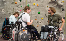 Gruppe junger Menschen im Rollstuhl in einer Sporthalle