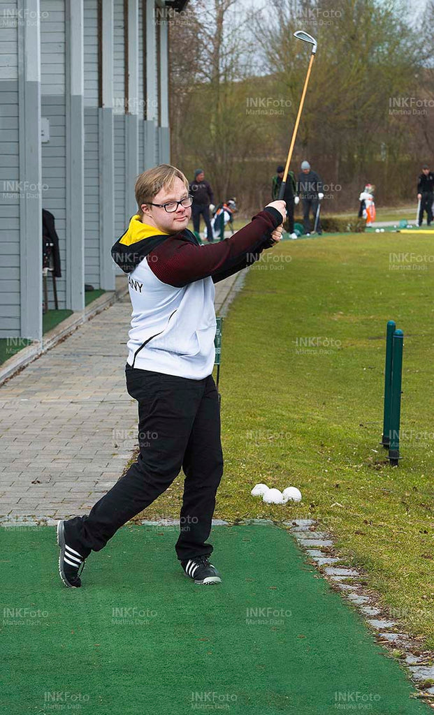Junger Mann mit Behinderung spielt Golf