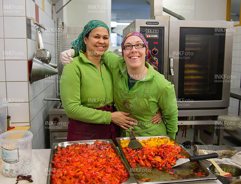 Zwei Frauen posieren Arm in Arm in einer Großküche