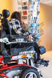 Frau im Rollstuhl am Postkartenständer
