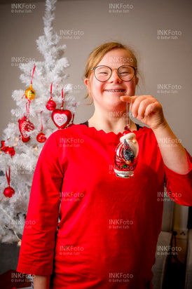 Junges Mädchen mit rotem Pullover beim schmücken des Weihnachtsbaumes