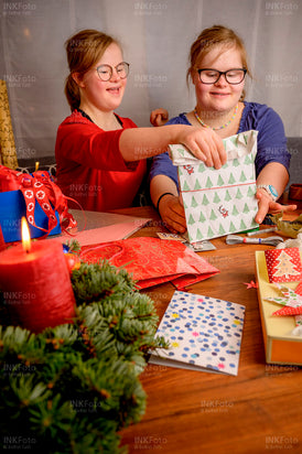 Zwei junge Mädchen packen Geschenke für Weihnachten ein.