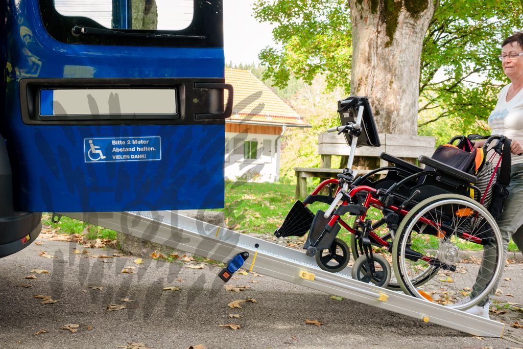 Frau schiebt einen Rollstuhl in einen Kleinbus
