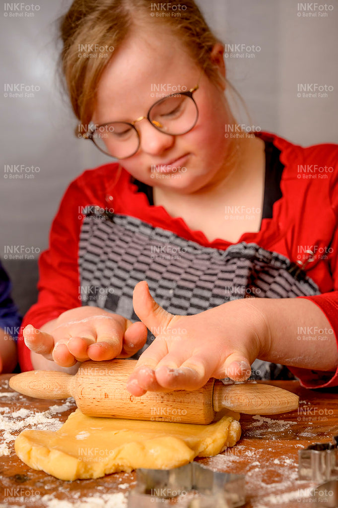 Junges Mädchen rollt Teig mit Nudelholz für Plätzchen aus