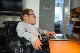 Mann im Rollstuhl am Laptop im Homeoffice