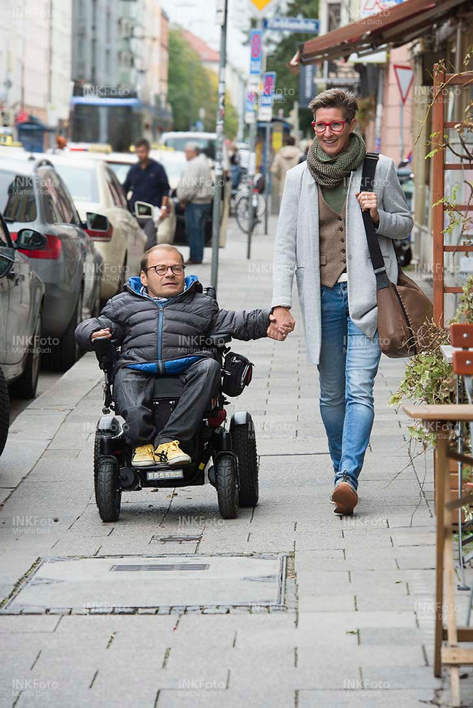 Mann im Rollstuhl mit Frau Hand in Hand in der Stadt. 