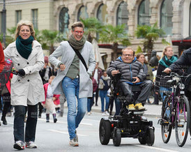 Mann im Rollstuhl mit Frau in der Stadt