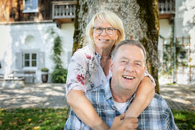 Ehepaar umarmt sich lächelnd im Garten in der Sonne